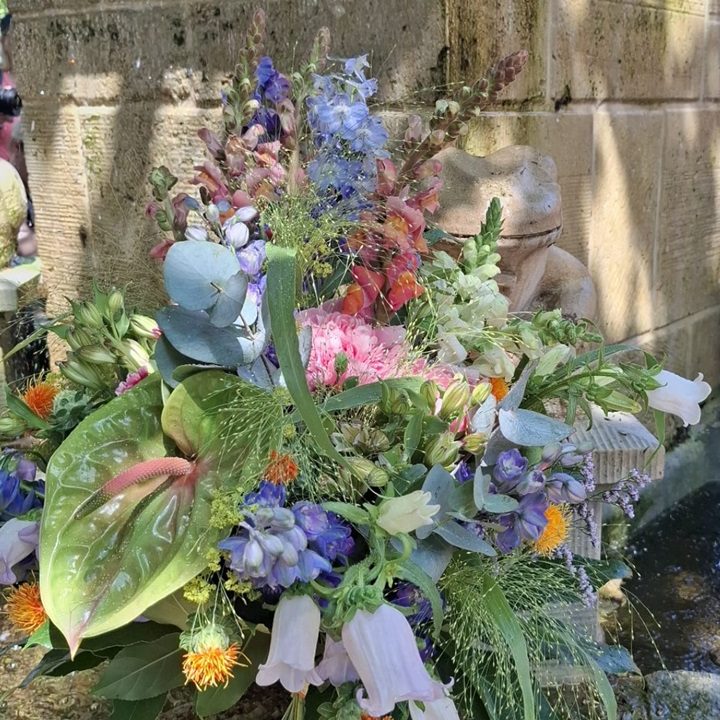 Bunte Blumenarrangements und Pflanzen auf einem Tisch mit Körben in einem Gartenmarkt.