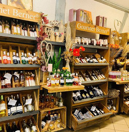 Regal mit verschiedenen Flaschen und Produkten, dekoriert mit Blumen und Holz.