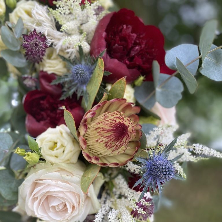 Bunter Blumenstrauß aus Rosen, Pfingstrosen, Disteln und Eukalyptus.
