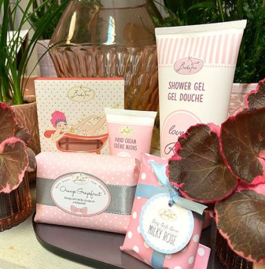 Verschiedene kosmetische Produkte in rosa und weiß, dekorativ angeordnet.