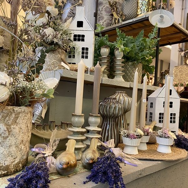 Blühende Pflanzen und Gartenmöbel unter einem Stoffdach.