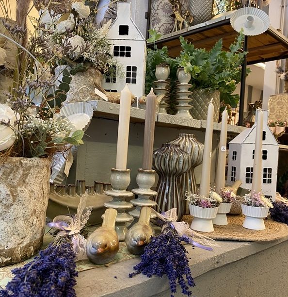 Dekorative Kerzenständer mit Lavendel und kleinen Deko-Häusern im Hintergrund.