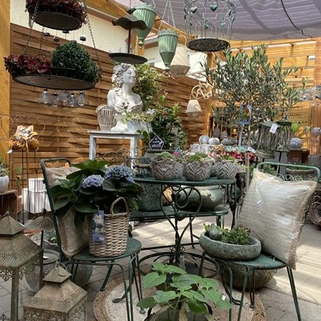 Grüne Keramikvasen und Töpfe mit Katzenmotiven sowie kleinen Pflanzen.